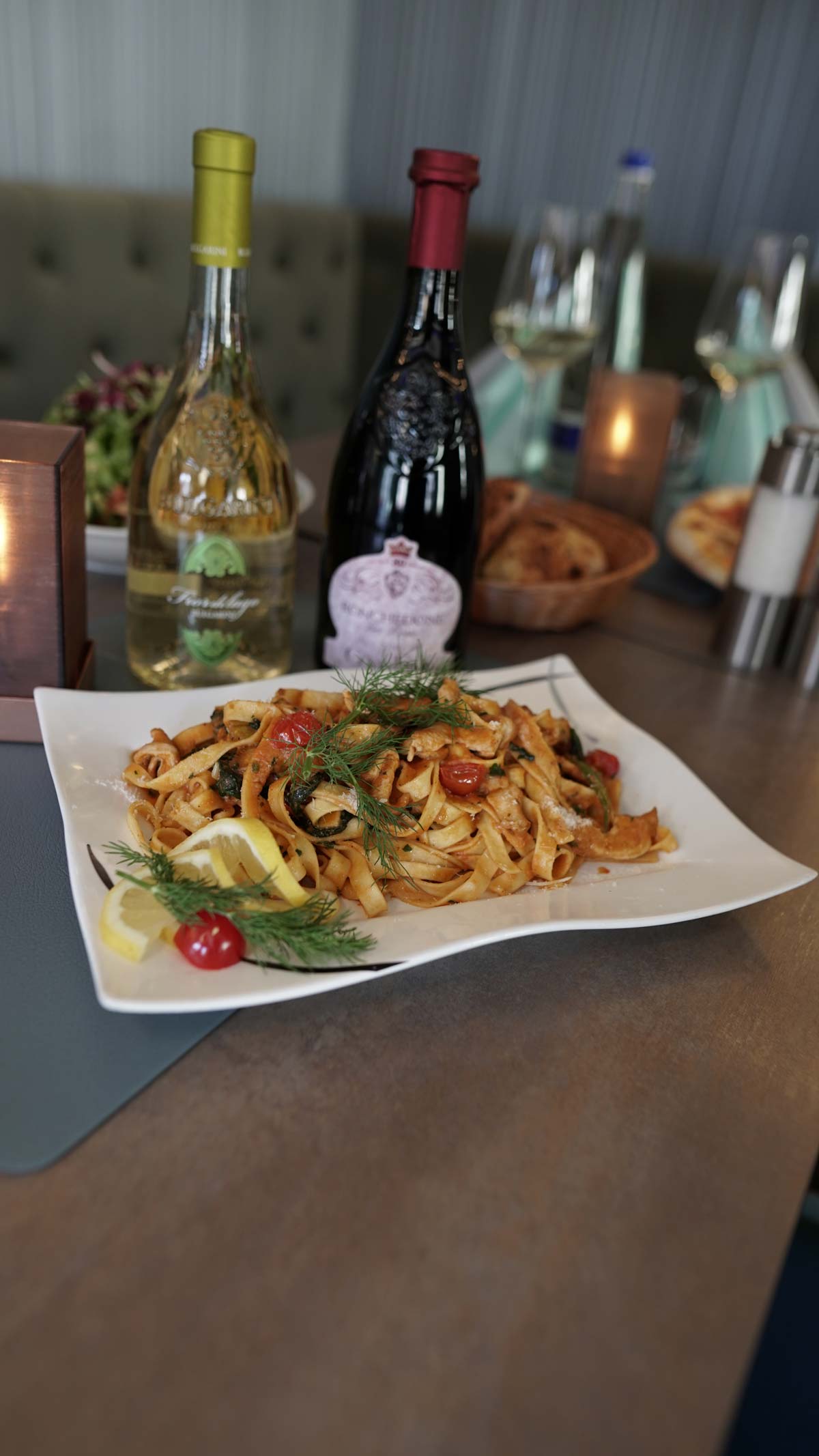 Teller mit Pasta, Wein im Hintergrund